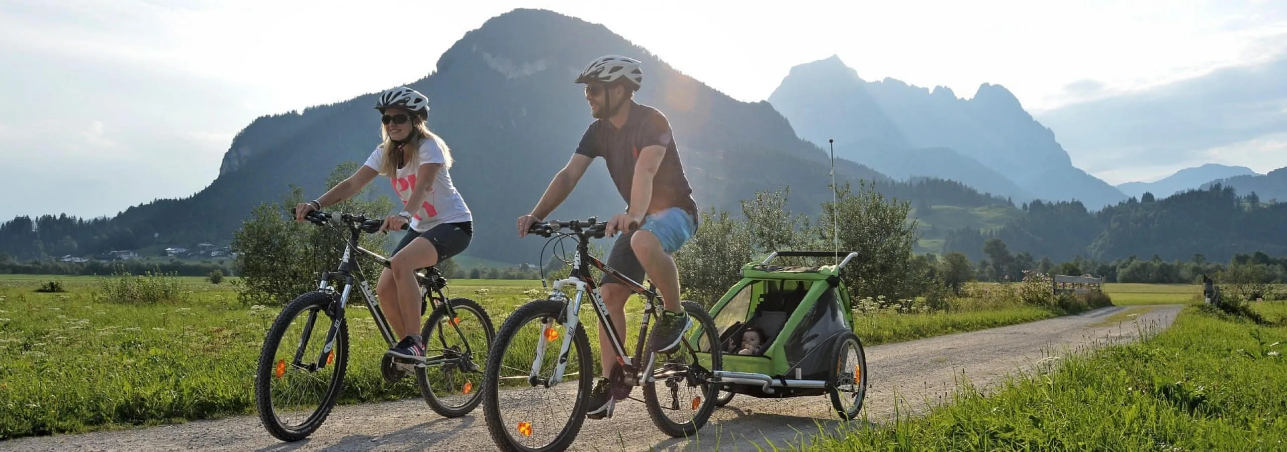 Familie radelt mit Kinderanhänger durch die Kitzbüheler Alpen