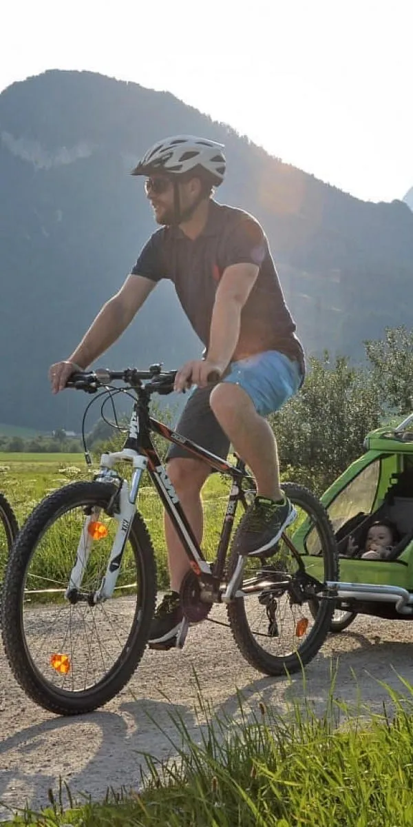 Familie mit Kinderanhänger radelt durch die Kitzbüheler Alpen