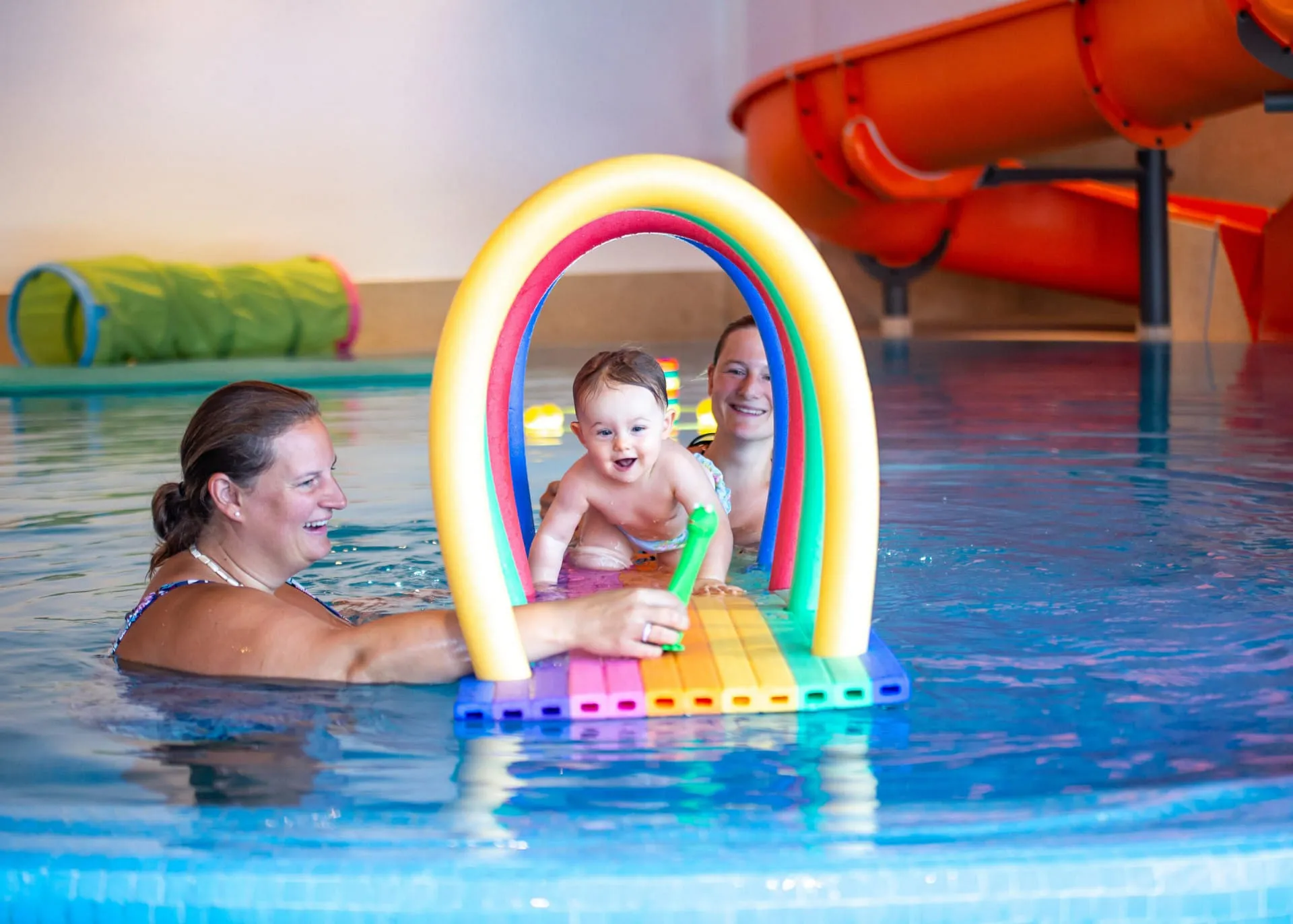 Mütter spielen mit Baby und Kleinkind im Hallenbad des Babymio