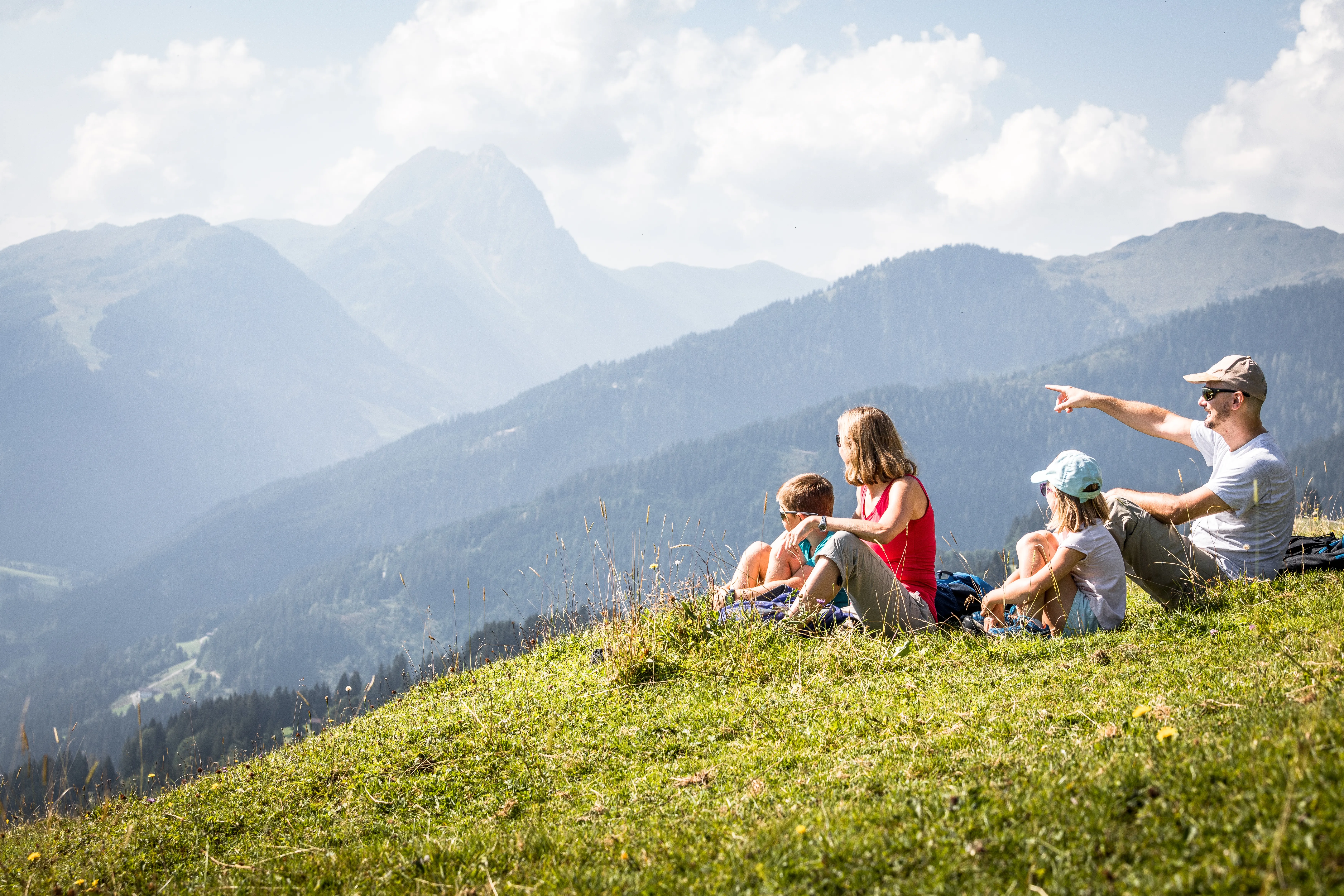 Familie genießt Bergblick auf die Kitzbüheler Alpen von einer Wiese